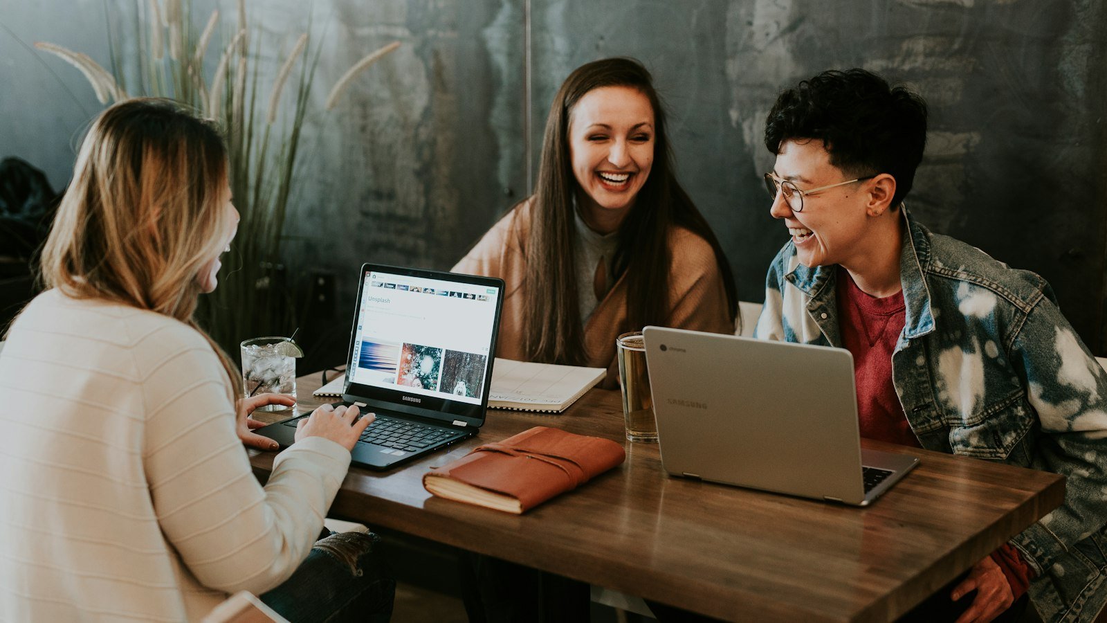 Friends working on laptops together at a cafe table