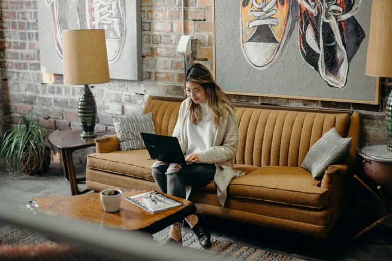 Woman working on a laptop on a sofa in a bright loft