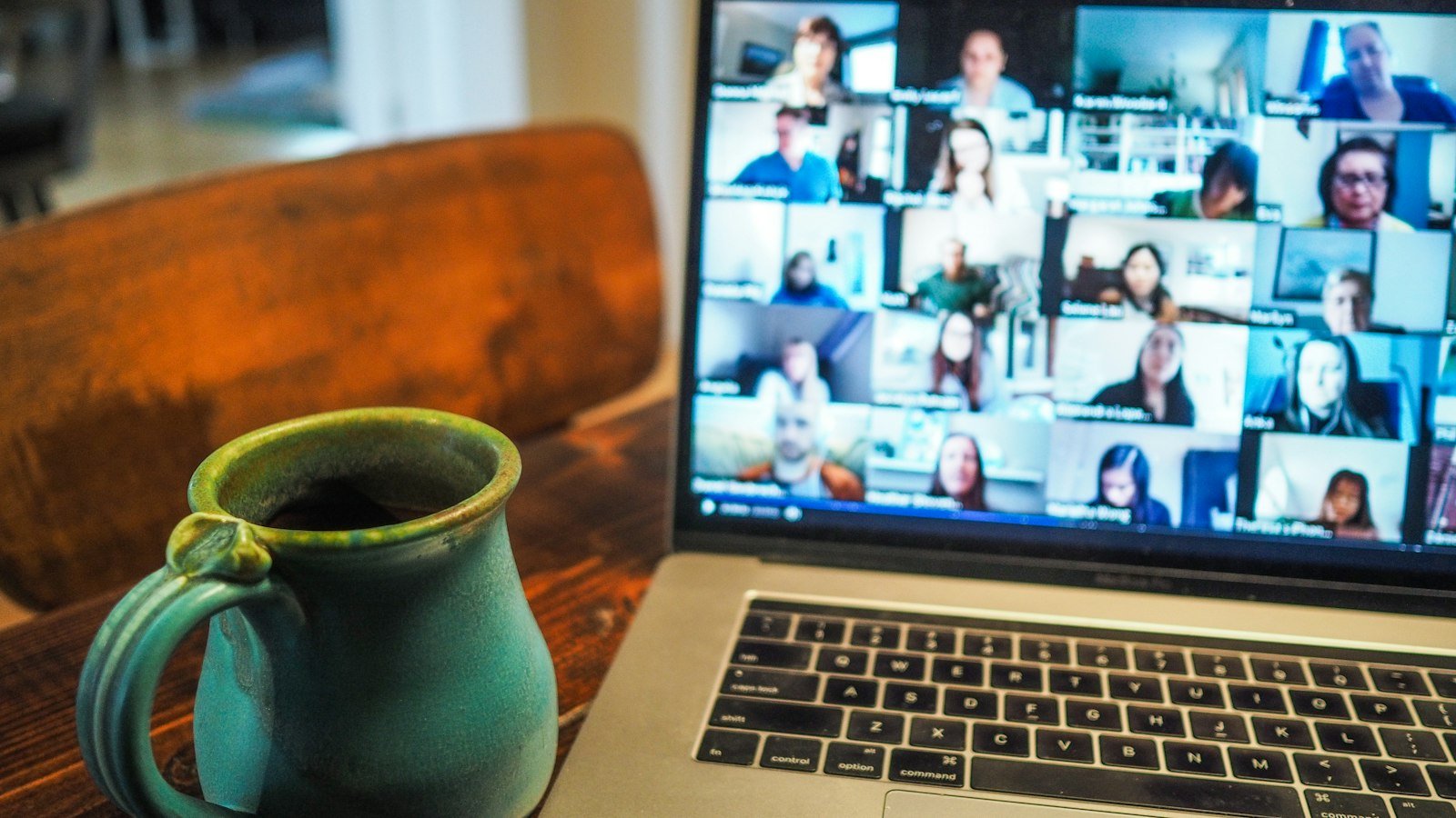 Laptop showing a video call with a coffee mug beside it