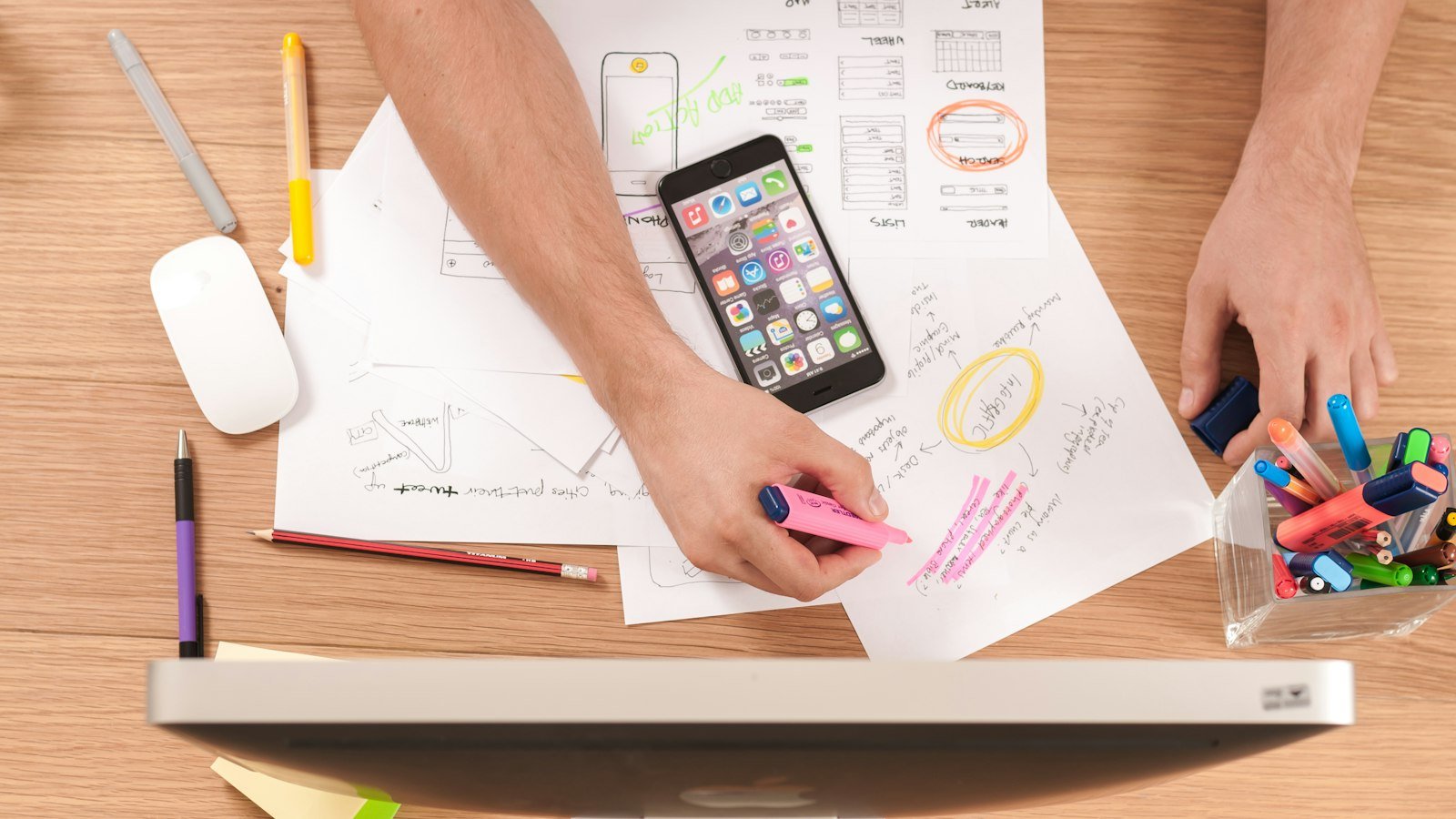 Person sketching plans on paper next to a smartphone