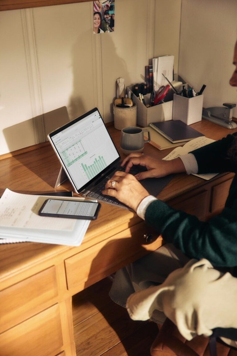 Person working on a laptop at a wooden desk on an online side hustle