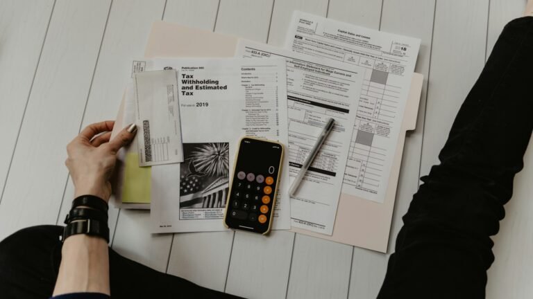 Tax forms, a calculator and a pen on a desk